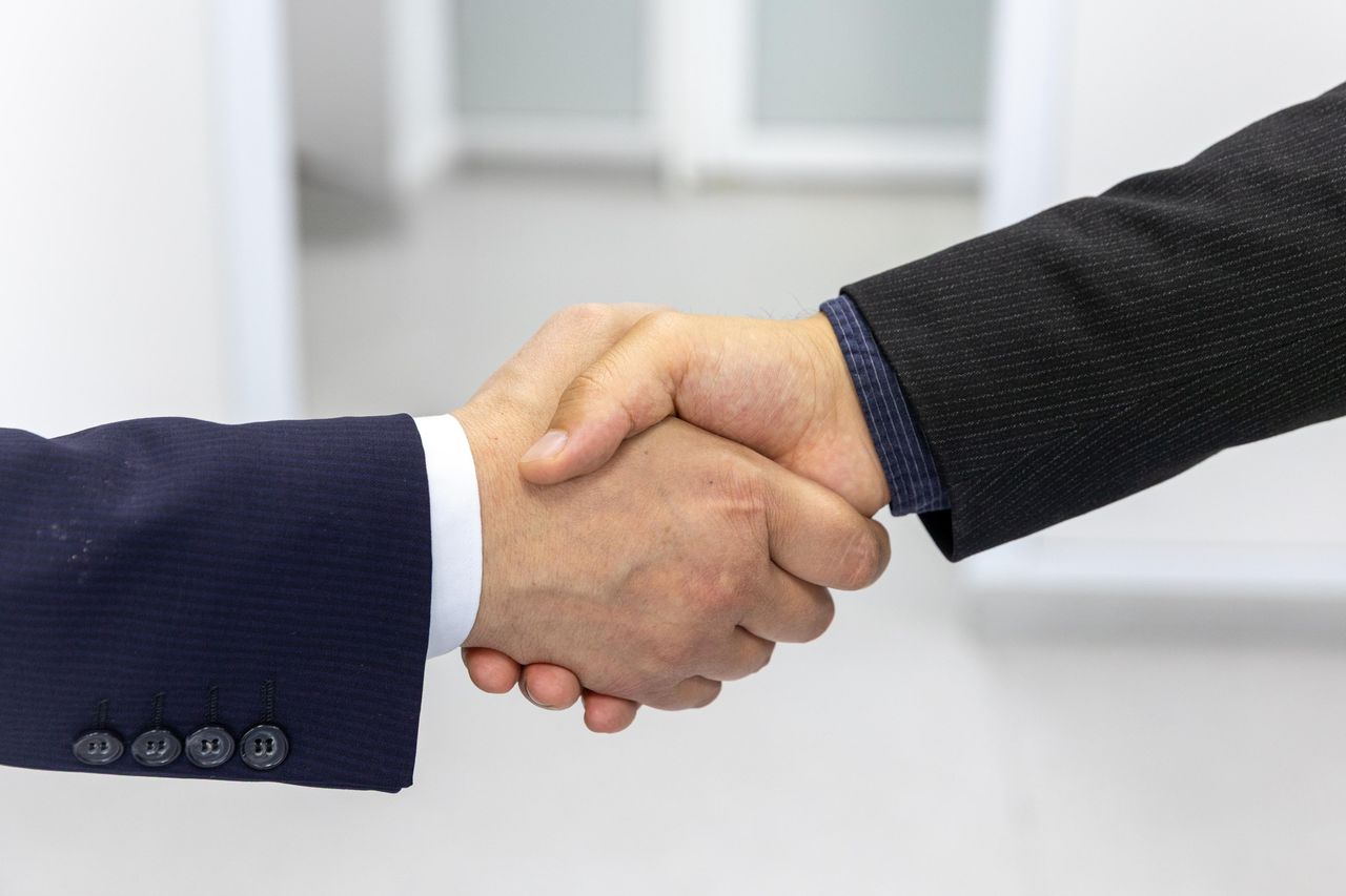 The Art of Drawing Readers In: Your attractive post title goes here Close-up of a handshake in a business environment, symbolizing partnership.